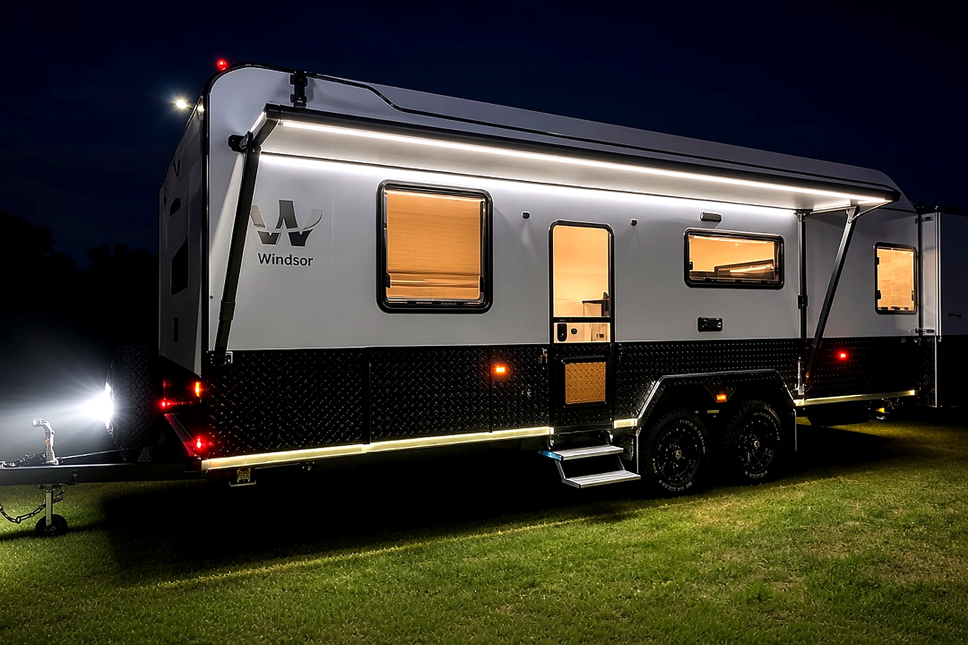 Caravan with exterior LED and 12V lighting illuminated at night